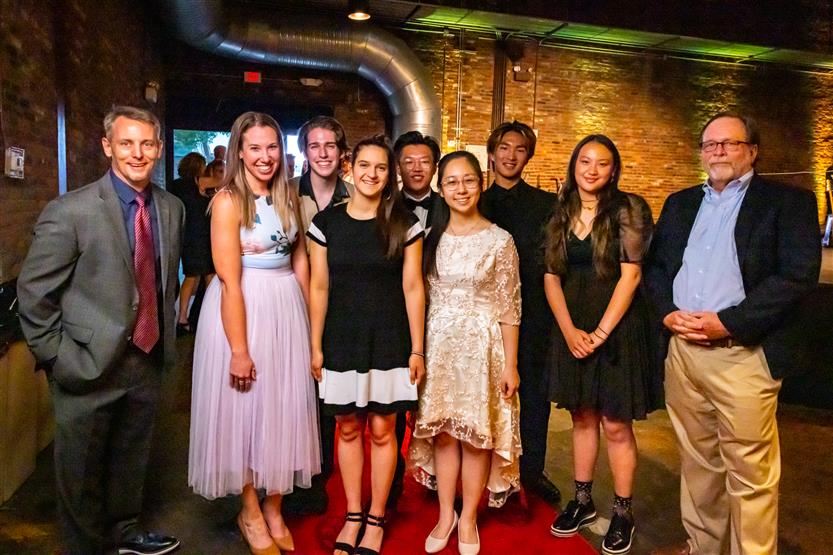 A group of students and two School Board members smile